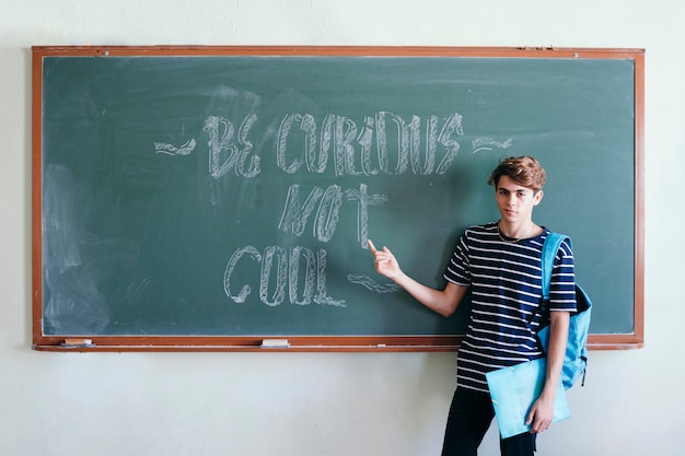 Student with backpack pointing the blacboard