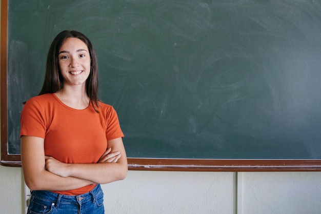 Student with blackboard smiling adn crossing her arms
