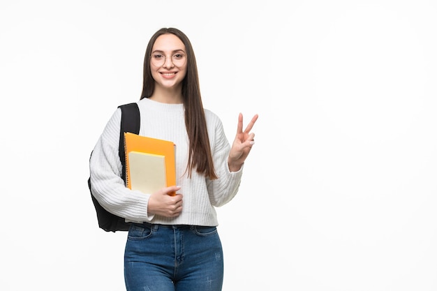 Student with books and backpack with peace gesture on white wall. Preparing for exam