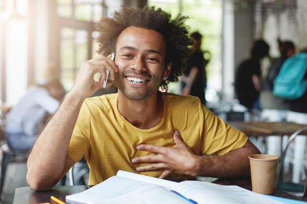 student with bushy hairstyle having pleasant conversation over cell phone