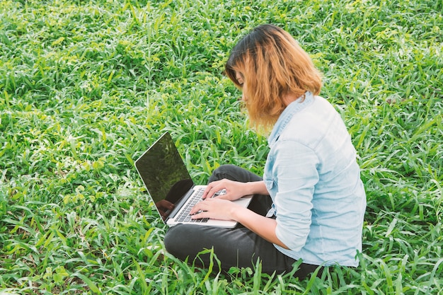 草の上に座ってノートパソコンと学生