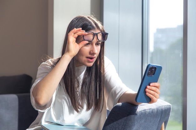 Free photo student woman with smartphone and notepads at the window in the morning