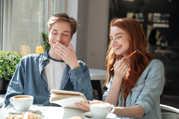 Студенты мальчик и девочка смеются в кафе