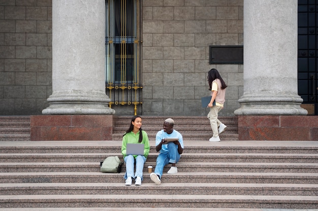 Students learning on stairs outdoors full shot