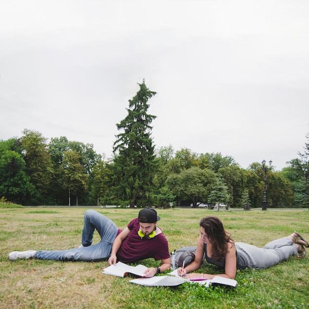 Free photo students lying on grass in park studying