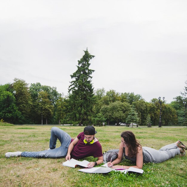 Students lying on grass in park studying