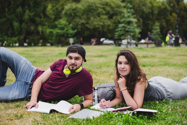 Students lying on grass with notebooks