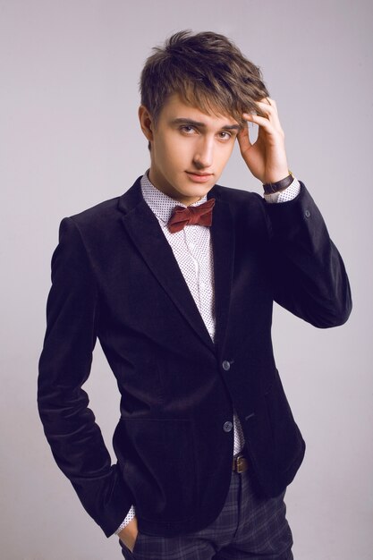 Studio fashion portrait of handsome men in stylish luxury suit and bow tie, light background, soft colors.