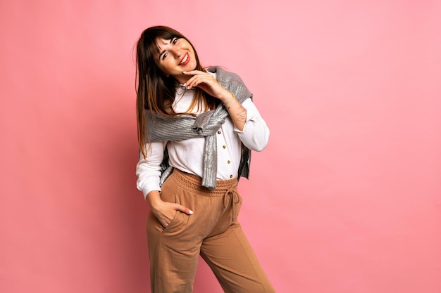 Studio indoor portrait of pretty brunette woman wearing casual winter outfit, posing at pink background, positive emotions.