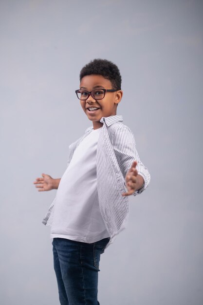 Studio photo of an emotional cute boy with the arms spread to the sides posing for the camera