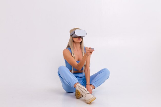 Studio photo of a young attractive woman in a warm blue fashionable suit wearing virtual reality glasses