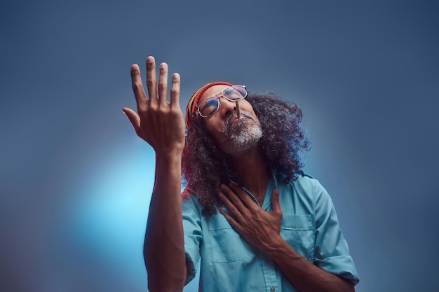 Free photo studio portrait of african rastafarian male smoking cigarettes. isolated on a blue background.