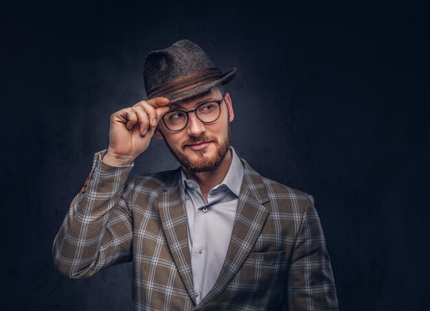 Studio portrait of a bearded hipster in hat and glasses wearing