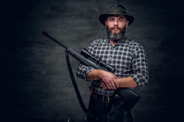 Free photo studio portrait of a bearded hunter holds a rifle.