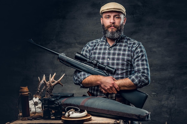 Studio portrait of a bearded traditional hunter with his trophy holds a rifle.