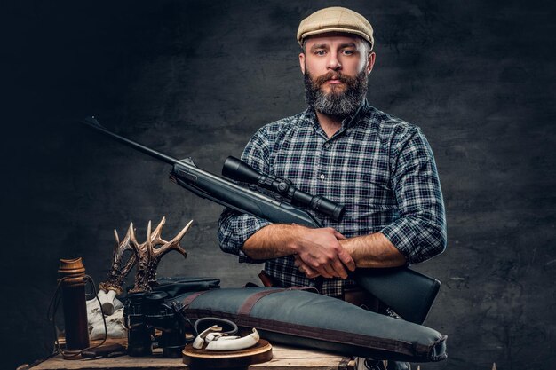 Studio portrait of a bearded traditional hunter with his trophy holds a rifle.