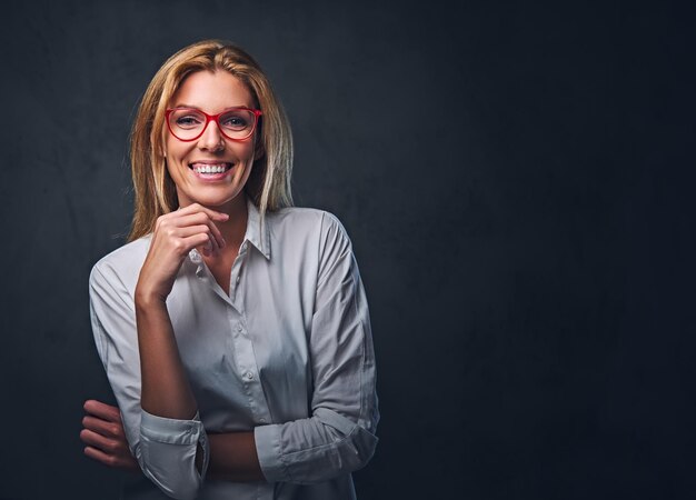 Studio portrait of blond female dressed in a white shirt and red eyeglasses.