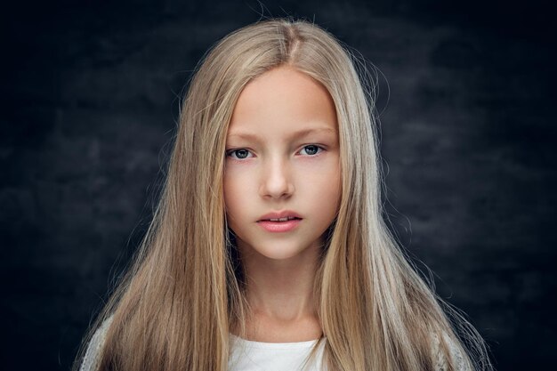 Студийный портрет блондинки-подростка на сером фоне.