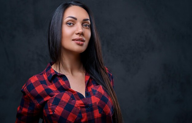 Studio portrait of brunette glamour hipster female dressed in a red fleece shirt over grey background.