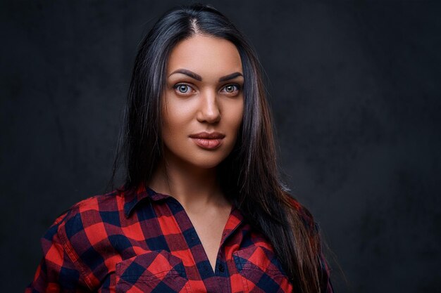 Studio portrait of brunette glamour hipster female dressed in a red fleece shirt over grey background.