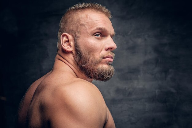 Studio portrait of brutal bearded muscular male over grey vignette background.