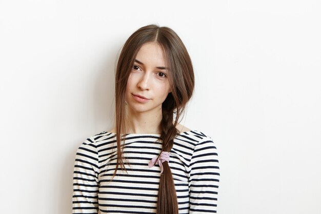 Studio portrait of charming young European brunette woman wearing striped top