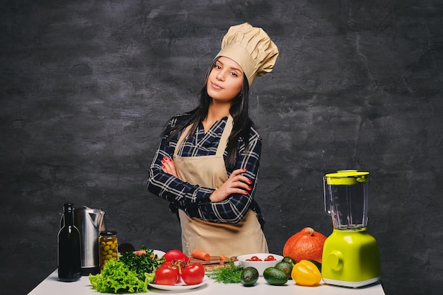 Foto gratuita ritratto in studio di chef donna cuoca al tavolo con un sacco di verdure.