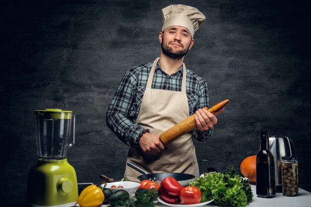 Studio portrait of a cook man with fresh vegetables on a table.