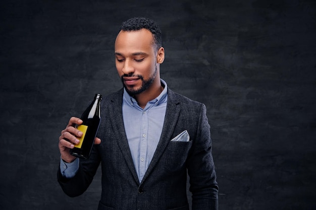 Studio portrait of elegant black American male dressed in a suit tasting craft beer.