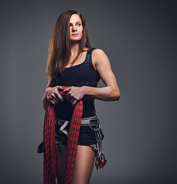 Free photo studio portrait of female free clamber holds, climbing rope over grey background.