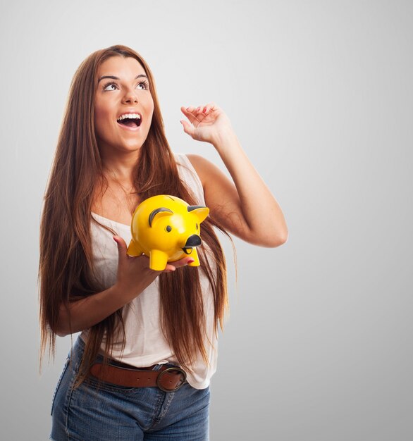 Studio portrait of girl holding yellow moneybox.