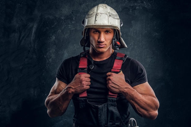 Free photo studio portrait of a handsome man wearing a fire helmet and gloves, looking at a camera