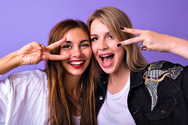 Studio portrait of pretty sisters best friends womanâs having fun together smiling screaming