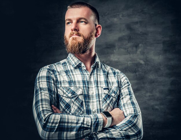 Studio portrait of redhead bearded male dressed in afleece shirt over grey background.