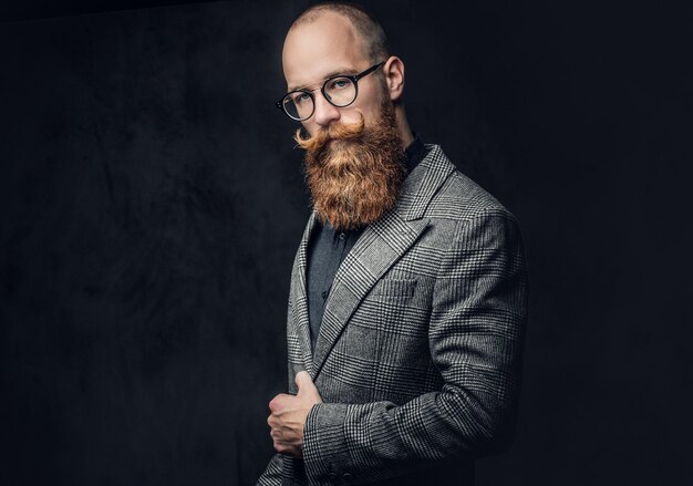 ウールのジャケットに身を包んだヴィンテージ眼鏡の赤毛のひげを生やした男性のスタジオポートレート。