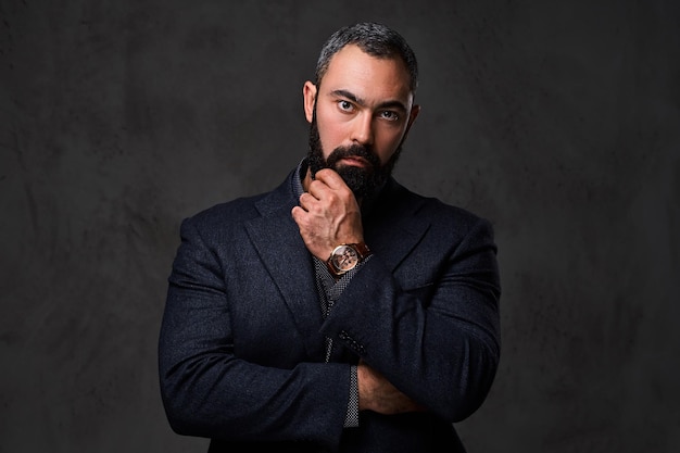 Studio portrait of serious, bearded male dressed in a suit.