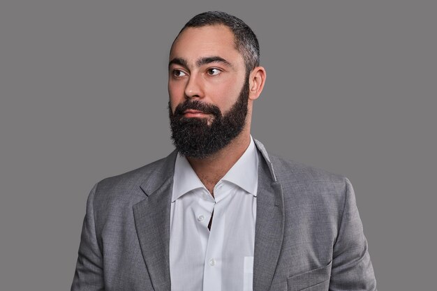 Studio portrait of serious, bearded male dressed in a suit.