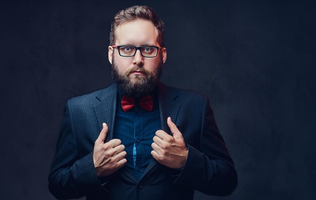 Studio portrait of serious plump male in eyeglasses over grey background.