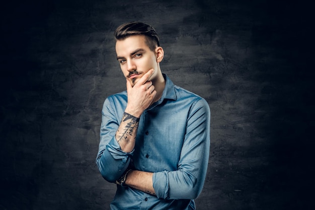 Studio portrait of thoughtful, casual male with tattoo on his arm.