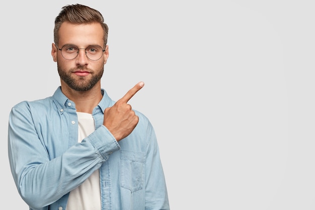 Studio shot of attractive bearded guy posing against the white wall