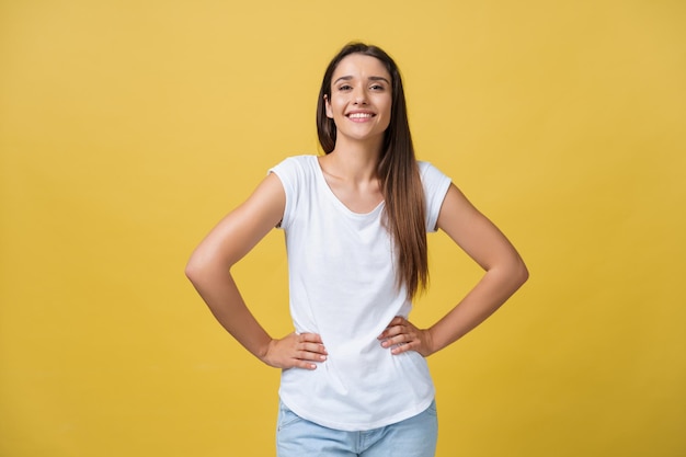 Studio shot of attractive self confident young female in great mood feeling happy holding hands on her slender waist and looking at camera with radiant smile