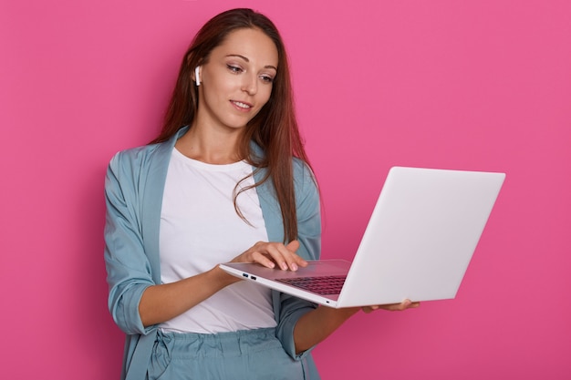 Studio shot of beautiful caucasian businesswoman holding white laptop