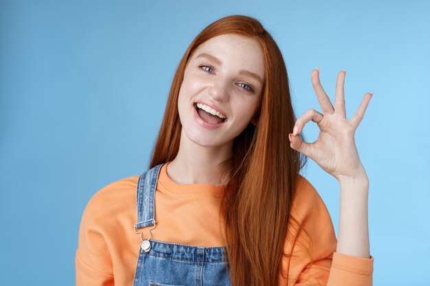 스튜디오 촬영 평온한 행복한 매력적인 유럽 빨간 머리 소녀 쇼 OK 사인 미소 하얀 치아 승인 확인 좋은 제품을 추천합니다.