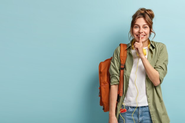 Studio shot of cheerful European woman makes silence gesture