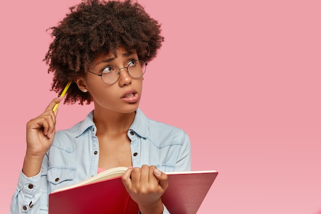 Free photo studio shot of contemplative lady scratches head with pencil