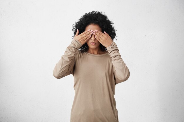 Studio shot of dark-skinned young female with black curly hair covering eyes