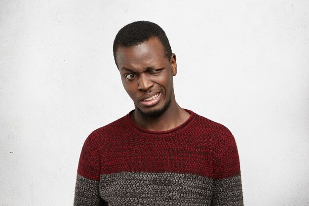 Studio shot of disgusted young African American man dressed casually