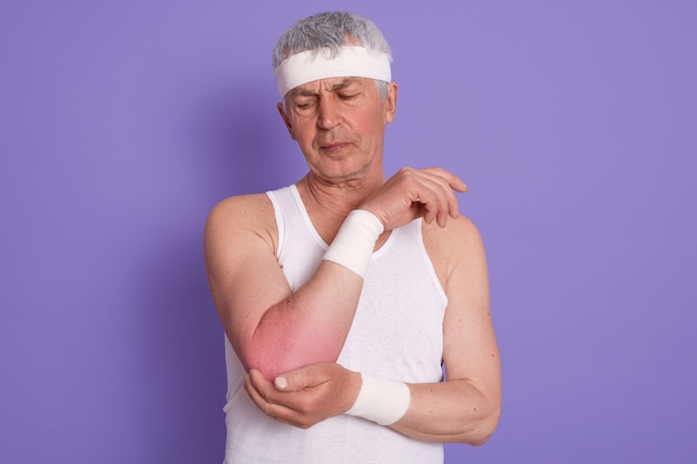 Studio shot of elderly man wearing white sleeveless t shirt and head band