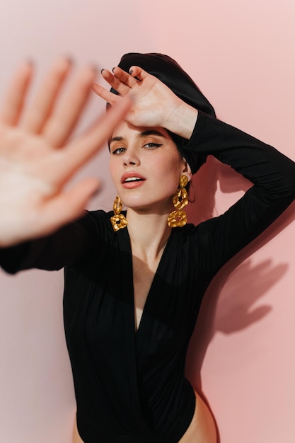 Studio shot of elegant girl in black outfit isolated on pink background Graceful caucasian lady posing in head scarf