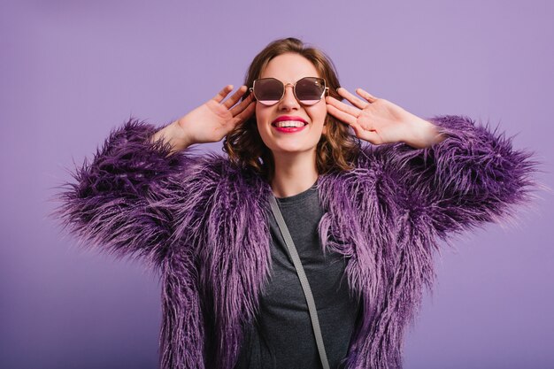 Studio shot of fascinating young woman with short hair laughing on purple background